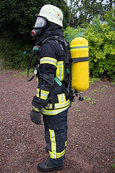 Brandeinsatz: Nomex-Jacke und Nomex-Überhose, Flammschutzhaube, Helm ohne Visier, Brandhandschuhe, Atemschutzgerät